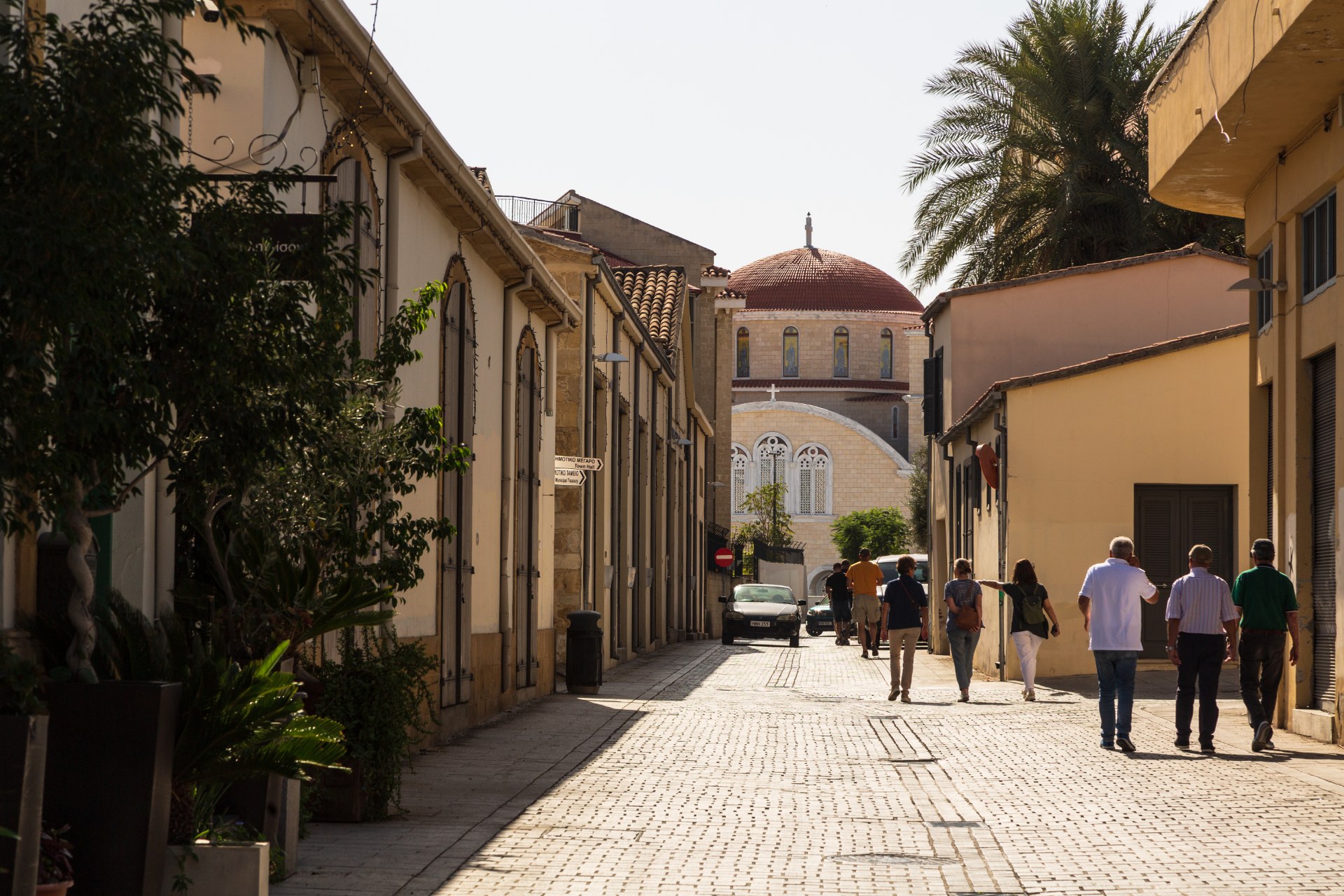 Gente caminando por una calle estrecha del casco antiguo de Nicosia hacia una catedral con cúpula